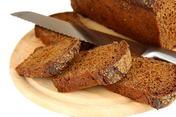 Sliced black bread and knife on wooden board close up