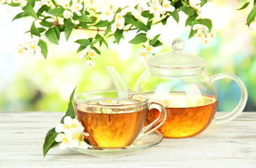 Cup of tea with jasmine, on wooden table, on bright background