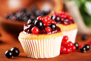 Tasty muffins with berries on wooden table