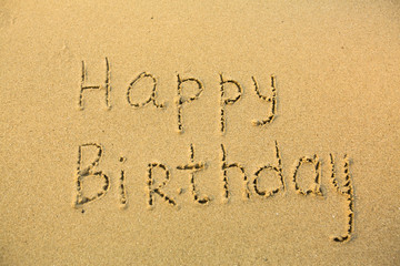 Fototapeta na wymiar Napis z okazji urodzin na tekstury mokrego piasku.