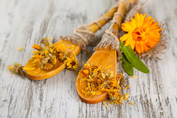 Fresh and dried calendula flowers on wooden background