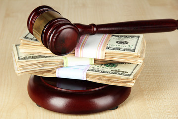 Stacks of money and judges gavel on wooden table