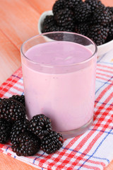 Sweet blackberries with yogurt on table close-up