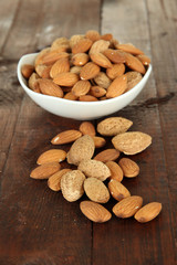 Almond in bowl, on wooden background