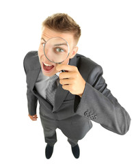 Young businessman looking through magnifying glass isolated