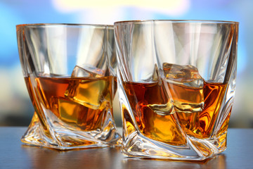 Glasses of whiskey, on bright background