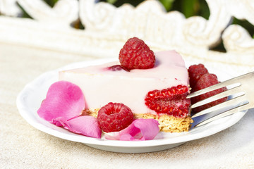 Piece of raspberry cake on wooden table in the garden.