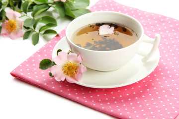 Cup of herbal tea with hip rose flowers, isolated on white