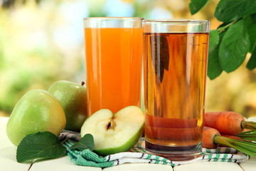 Glasses of juice, apples and carrots