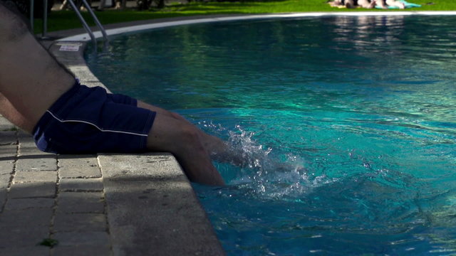 Man splashing water in the swimming pool, slow motion shot at 24