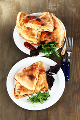 Pizza calzones on plates on wooden table