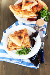 Pizza calzones on plates on napkin on wooden table