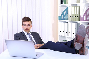 Businessman resting at his office with his shoes on table