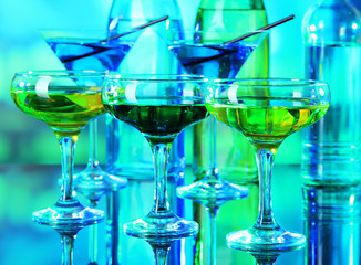 Glasses of cocktails on bright background