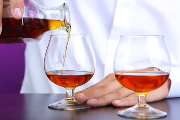 Bartender is pouring cognac into glass