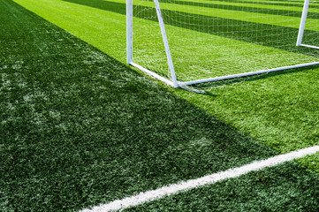Empty soccer field with goal posts and light poles.