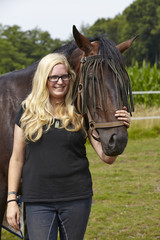 Fototapeta premium Schwarzer Oldenburger mit junger, blonder Frau