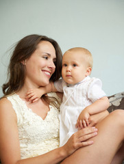 Happy woman holding cute baby indoors