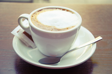 White cappuccino cup standing on the wooden table
