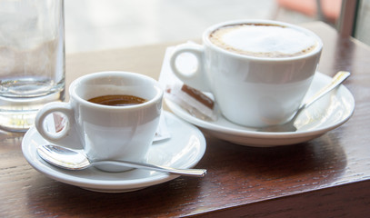 Espresso and cappuccino cups standing on the wooden table