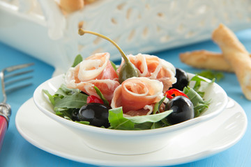 Salad with arugula, prosciutto and olives.