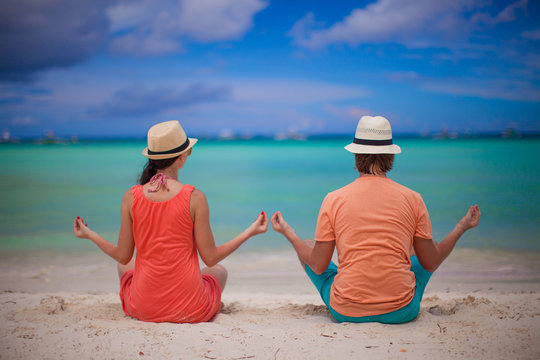 Young couple enjoying each other and yoga on a beach