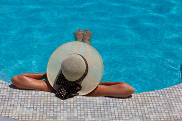 Fototapeta na wymiar Woman in hat relaxing at the pool