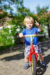 Fototapeta na wymiar Little toddler boy riding on his bycicle in summer