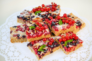 red and black currant berries with home baked cake on background