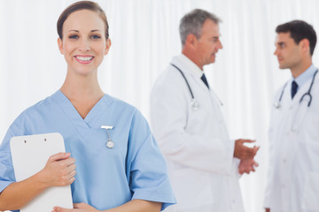 Smiling surgeon posing while doctors talking on background