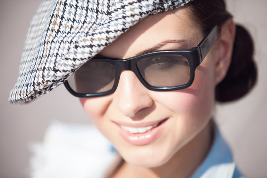 Close-up portrait of beautiful smiling girl with hat and glasses