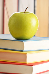 Composition with green apple and books on the table
