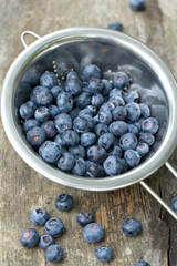 blueberries in a small colander on wooden background