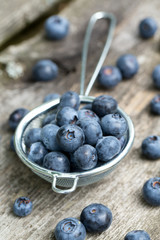 blueberries in a small colander on wooden background
