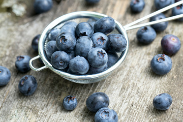 blueberries in a small colander on wooden background