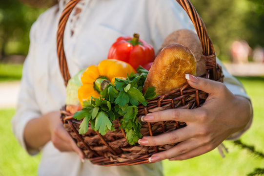 Unrecognizable woman holding basket full of vegetables and bread