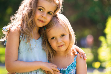 Outdoor portrait of two embracing cute little girls