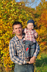 Fototapeta premium Dad keeps his son in his arms in the autumn forest