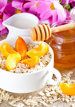 Apricot in the bowl, oatmeal, honey and milk jug