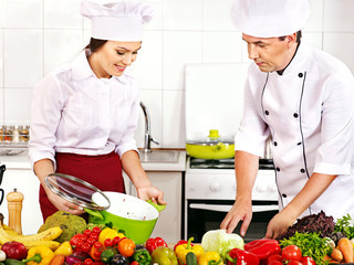 Man and woman in chef hat cooking.