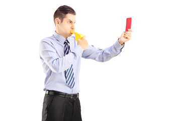 Young man blowing a whistle and showing a red card