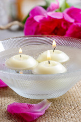 Floating candles in water among rose petals. Aromatherapy in spa