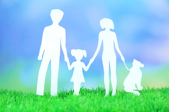 Family from paper on grass on bright background