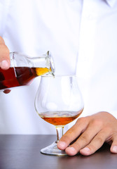 Bartender is pouring cognac into glass