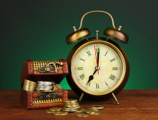 Antique clock and coins on wooden table on dark color