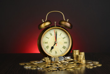 Antique clock and coins on wooden table on dark color