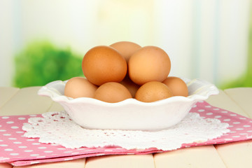 Eggs in plate on wooden table on natural background