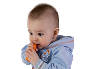 Smiling baby eats carrot