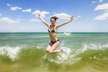 Girl jumping and splashing in the waves of the sea