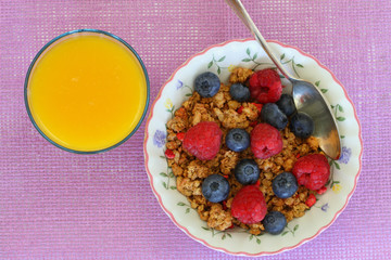 Breakfast cereal with raspberries and blueberries, orange juice